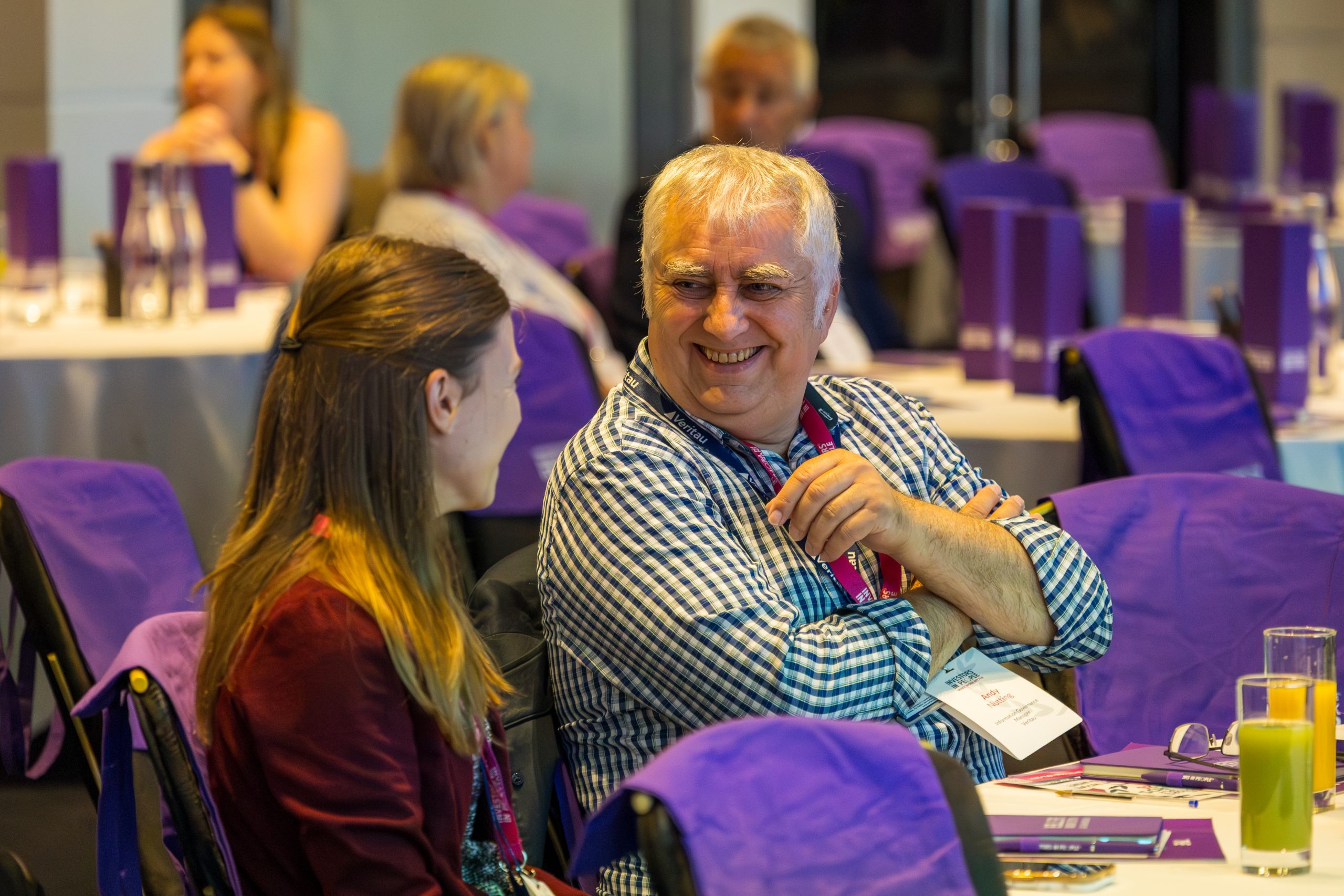 Two people sat next to each other at the Investors in People Event talking and smiling